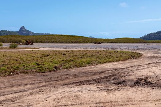 Car Tracks And A Rusting Wreck On Tidal Salt Flats