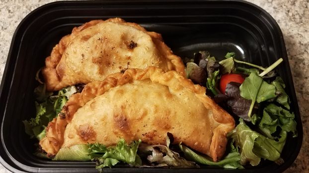 Puerto Rican fried beef turnover and salad in container