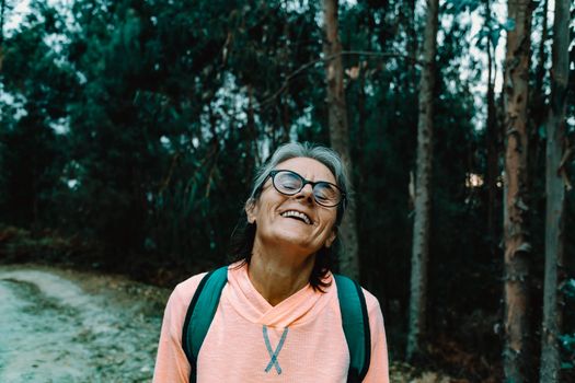 Old woman laughing in the middle of the forest in spain wearing sport clothes