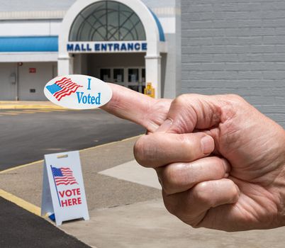 Hand with sticker by entrance to a polling place for elections in old Mall