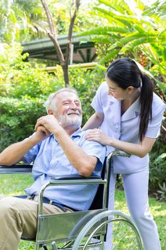 A nurse take care a senior male on wheelchair in his garden at h