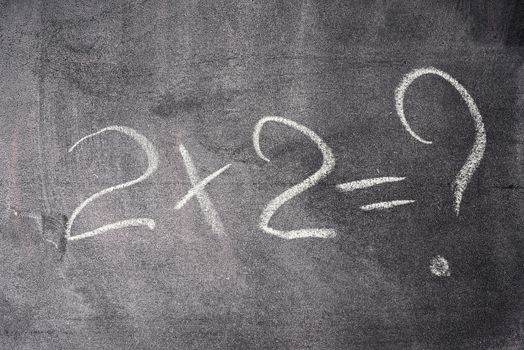 mathematical example two times two is written in white chalk on 