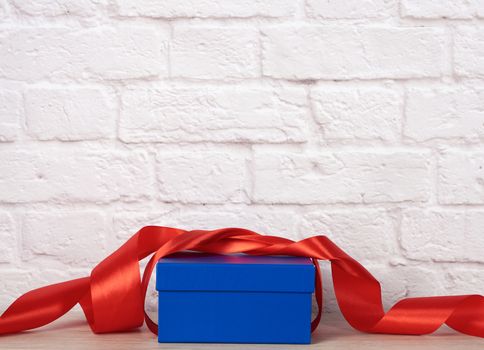blue cardboard box with gift and red silk ribbon