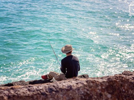 Retiree Male Fishing From Breakwater Rocks