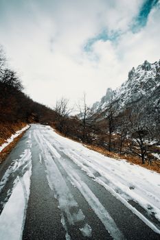 Road on the mountains covered with snow and a mountain range as the background