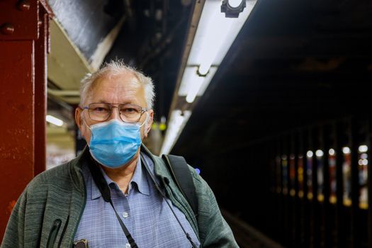 Old man in medical mask standing in the subway coronavirus epidemic