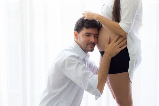 Asian man father ear listening to the belly of the pregnant wife