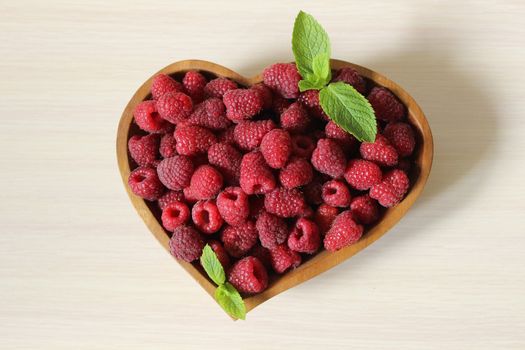 Large quantity of sweet raspberries in a wooden container