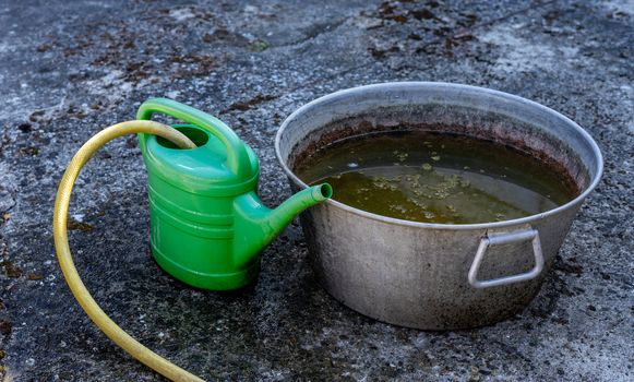 Watering can with rainwater and zinc tub for the garden