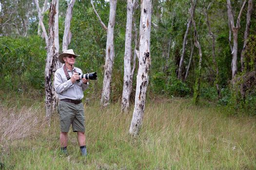 Photographer Holding Camera And Long Lens In Bushland