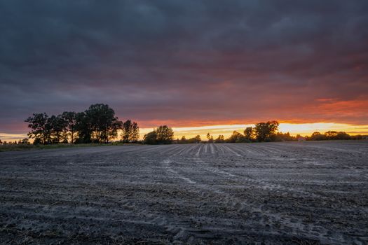 Ploughed field and dark clouds during sunset