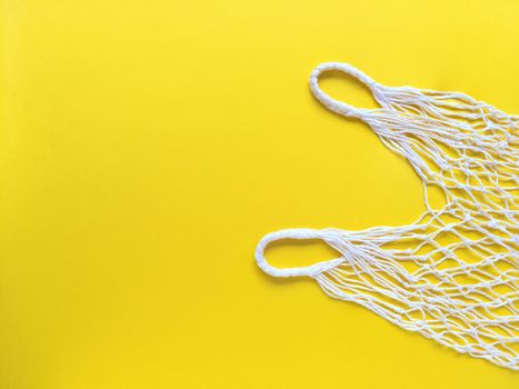 White string cotton eco bag on yellow background. Simple flat lay with copy space. Ecology zero waste concept. Stock photography.