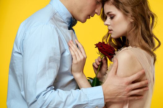Enamored man and woman with red rose on yellow background cropped view close-up romance. High quality photo