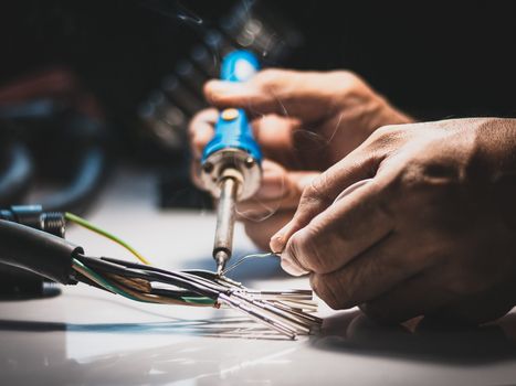 Electricians are using a soldering iron to connect the wires to 