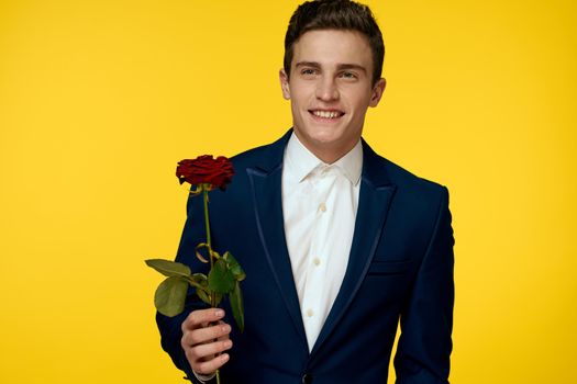 Gentleman in classic suit on yellow background with red rose romance