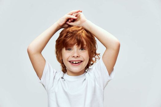 Cute redhead boy holding hands on head smile fun white t-shirt