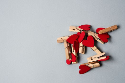 Clothespins with wooden hearts at the end on a gray background Valentine's day holidays decoration