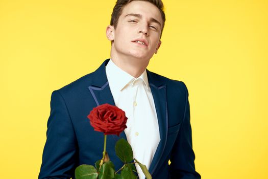 Gentleman in classic suit on yellow background with red rose romance