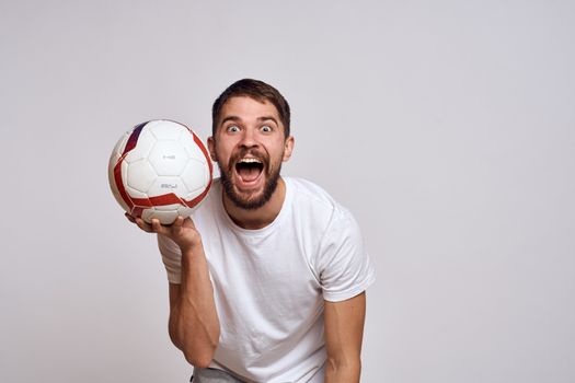 Male coach with a soccer ball in his hands on a light background energy explanation of movements