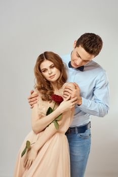Young couple romance hug relationship dating red rose light studio background. High quality photo