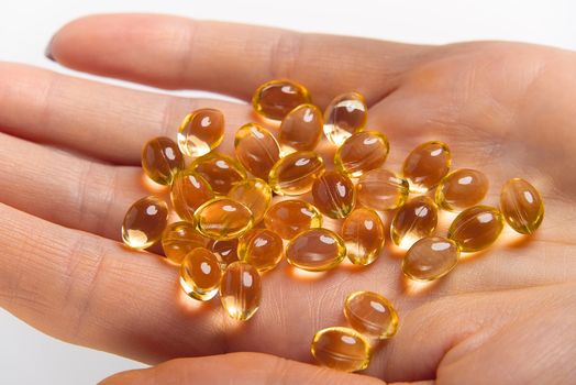 Women hand with gel capsules of D Vitamin . Vitamin Omega-3 fish oil in capsules. hand holding gelcap or softgel transparent capsule pills
