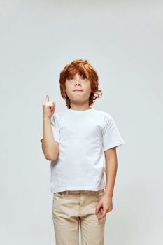 Redhead boy showing index finger up white t-shirt cropped view