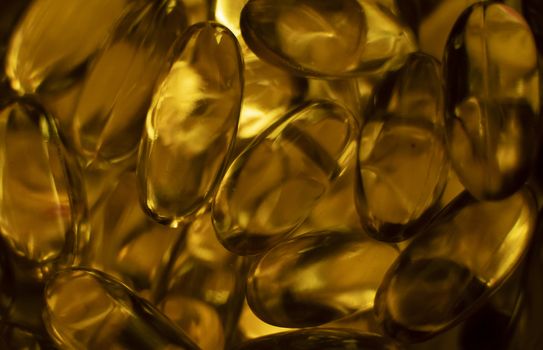 Extreme close up of fish oil orange yellow softgels capsules fish oil omega 3 or omega 6, omega 9, vitamin A, vitamin D, vitamin E background. Healthy vitamins product concept.