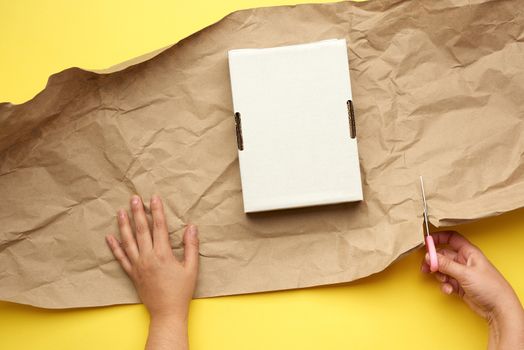 rectangular white cardboard box and two female hands are wrapped