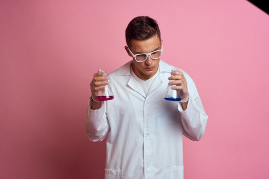 Male laboratory assistant with flasks in the hands of a multicolored liquid chemical substance