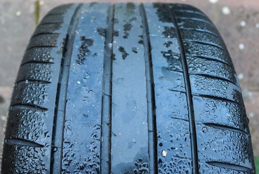 Black big tires in a close up view with water drops. Tire tread 