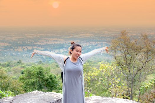 Asian women standing poses, arms outstretched on the top of the mountain.