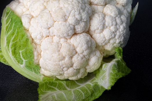Cauliflower. Raw vegetable on a black background. Front view.
