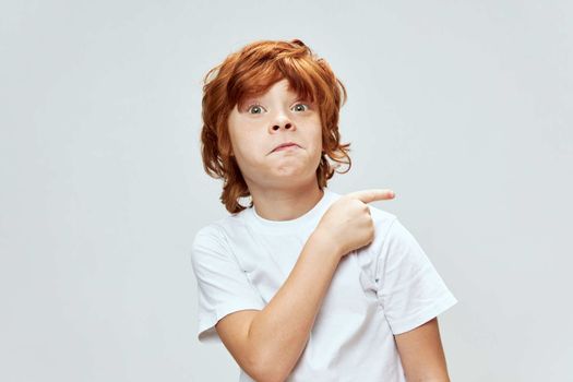 red-haired child white t-shirt hand gesture showing side emotion cropped view