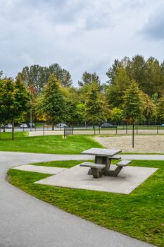 Picnic table and benches on green lawn in a park. Urban recreation area