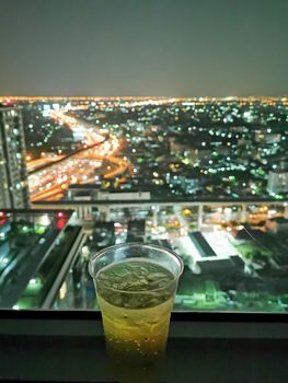 A glass of beer with cityscape from high condominium view at nig