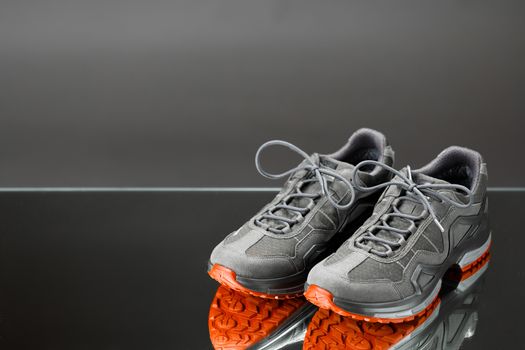 trekking sneakers with red sole, gray background with copy-space