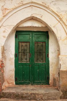 Old abandoned house facade with green wooden door