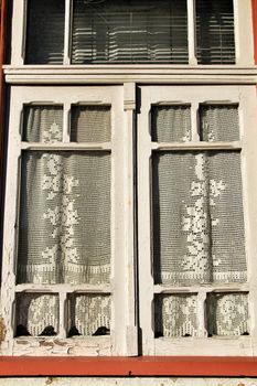 Wooden window painted in white and with crochet curtain