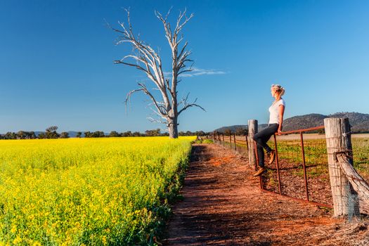 Country woman basking in the spring sunshine looking out over the canola fields
