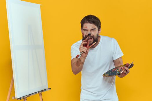 Male artist palette easel drawing hobby lifestyle creativity yellow background. High quality photo