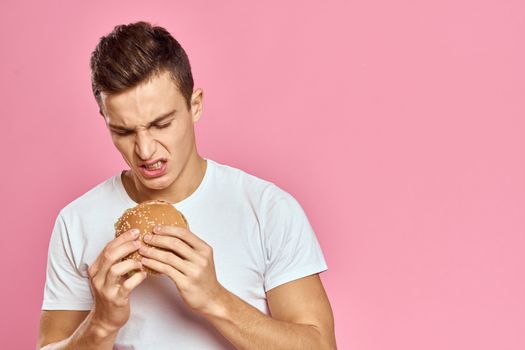 man with big hamburger on pink background calories fast food cropped view Copy Space close-up