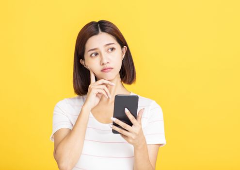 young asian woman holding mobile phone and looking away