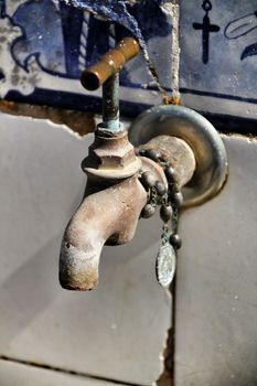 Old Tap with rosary beads in blessed fountain