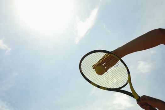 Person hold racket and ball against sky, space for text