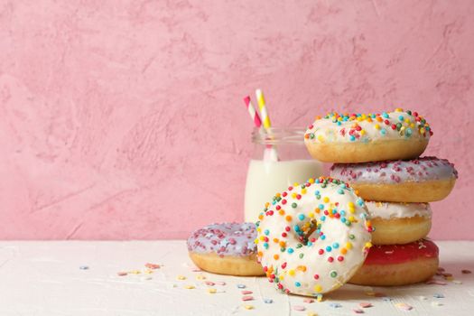 Milk and tasty donuts against pink background