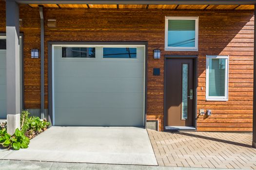Entrance and garage doors of brand new townhouse with wooden siding wall siding.