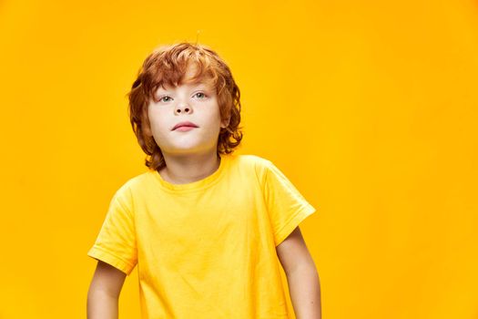 Red-haired child front view yellow isolated background interested facial expression