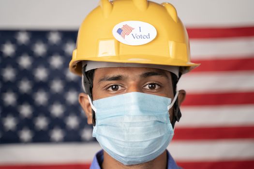 Head shot, I voted sticker on worker hardhat with US flag as background - Concept of USA elections and voting.
