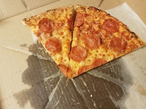 pepperoni pizza slices with grease in cardboard box