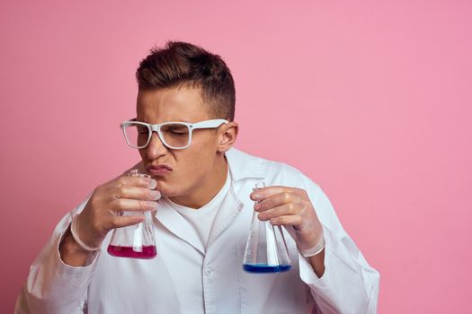 Male laboratory assistant with flasks in the hands of a multicolored liquid chemical substance